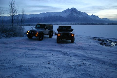 2003 Jeep TJ - Two Jeep TJs are parked in a snowy landscape with mountains in the background.