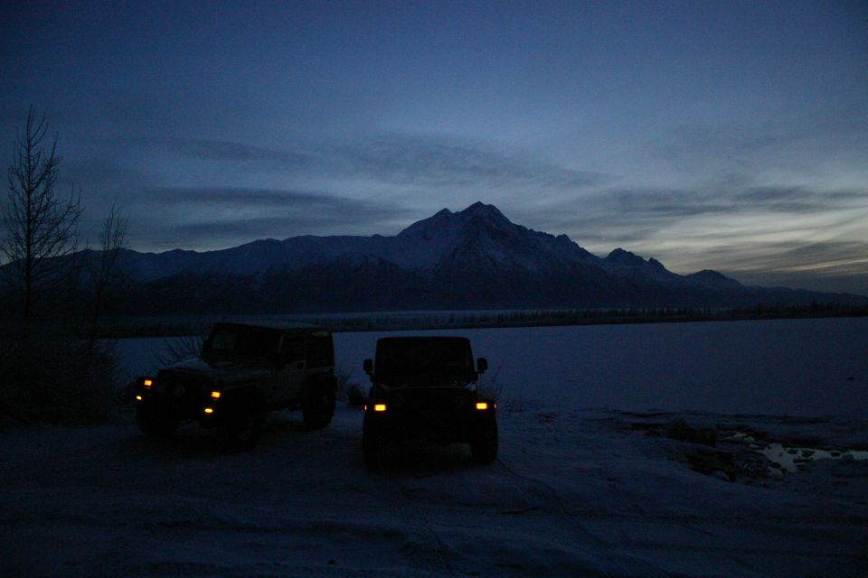 Two Jeep Wranglers parked in snow with mountains in the background at twilight