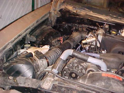 1973 Ford Ranchero - Close-up view of a vehicle's engine bay, showing the air intake system and alternator. A caution label is visible on the fan shroud.