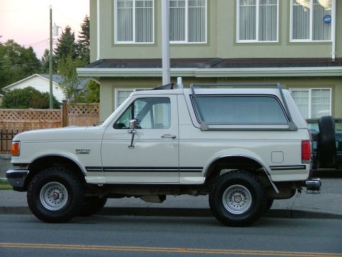 1988 Ford Bronco - This Ford Bronco is parked on the street in front of a house. It has a white exterior and a removable hardtop.