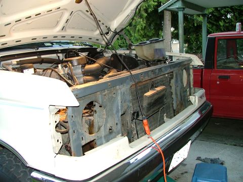 1988 Ford Bronco - Working on the engine bay of a 1988 Ford Bronco, with a red truck parked nearby.