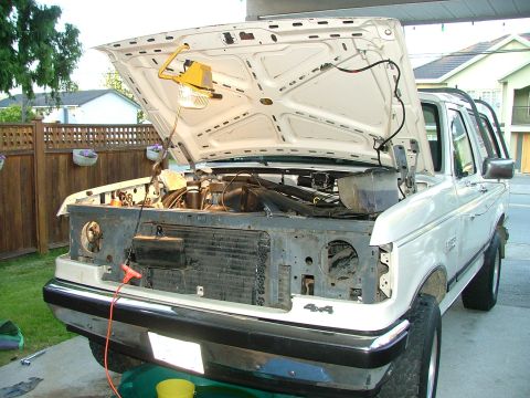 1988 Ford Bronco - Front view of a white 1988 Ford Bronco with its hood open, revealing the engine compartment. A '4x4' badge is visible on the front fender.