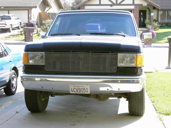 Front view of black Ford Bronco with billet grille and chrome bumper in a driveway, California plate 4CVB051