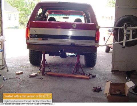 1991 Ford Bronco - The rear of a red 1992 Ford Bronco is elevated on jack stands inside a garage.