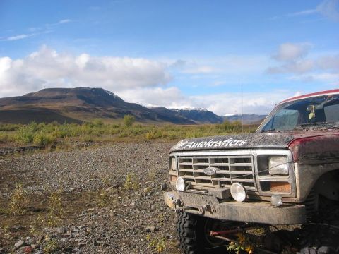 1985 Ford Bronco - Front view of a muddy 1980 Ford Bronco with 'Autokrafters' decal on the hood, in a scenic, rocky landscape.