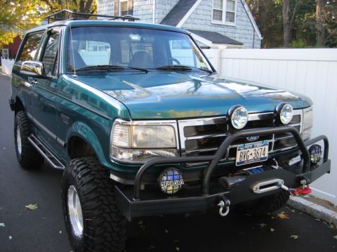 1991 Ford Bronco - Green Ford Bronco with a custom front bumper and winch, seen from a 3/4 front angle.
