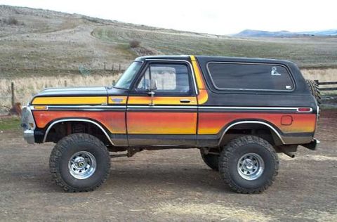 1993 Ford Bronco - Side view of a lifted 1978 Ford Bronco a custom gradient paint job and off-road tires.