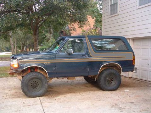 1993 Ford Bronco - This Ford Bronco is parked in front of a garage with trees in the background.