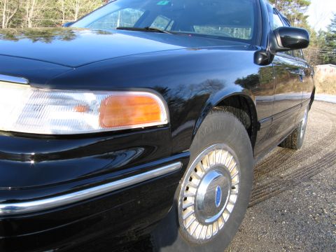 1991 Ford Crown Victoria LTD - The front passenger side of a black sedan is captured in this close-up shot.