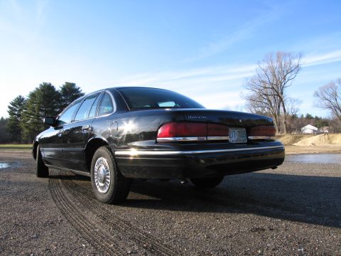 1991 Ford LTD Crown Victoria - This black 1991 Ford Crown Victoria LTD is shown from the rear three-quarter angle on a gravelly surface.