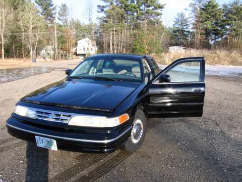 1991 Ford LTD Crown Victoria - A black 1991 Ford Crown Victoria LTD is parked on a gravel lot with the driver's side door ajar.