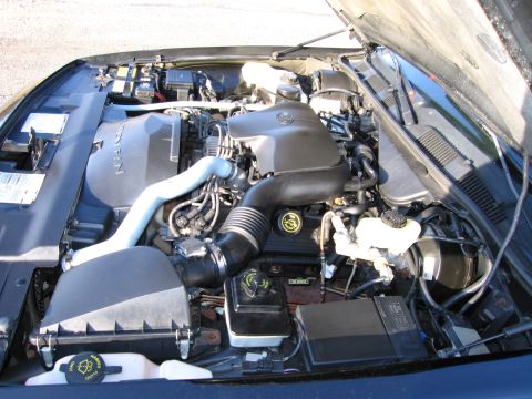 1991 Ford LTD Crown Victoria - Overhead view into the engine bay of a dark Ford with the hood up, showing a modular V8 with black plastic intake manifold, corrugated air…