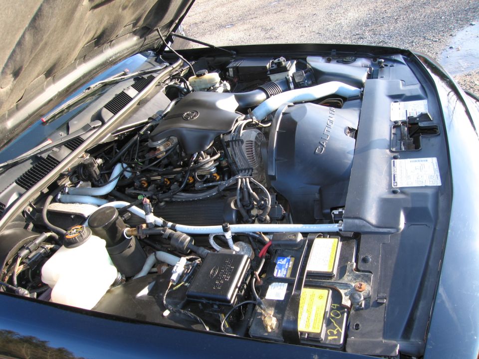 engine bay with hoses, battery, and fan shroud visible