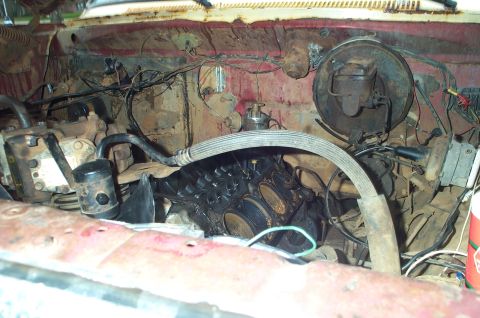 1978 Dodge Power Ram - The engine bay of a vehicle shows exposed cylinder heads, hoses, and wiring amidst rust and grime.