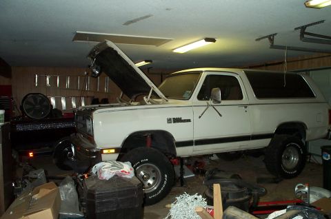 1978 Dodge Power Ram - A white Dodge Ramcharger SUV is parked in a garage with its hood up, showing modifications like a lift kit and larger tires.