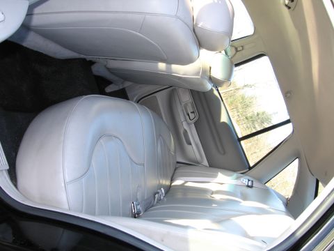 1991 Ford LTD Crown Victoria - The interior of a car shows light gray leather seats and door panels, with a view of trees through the window.