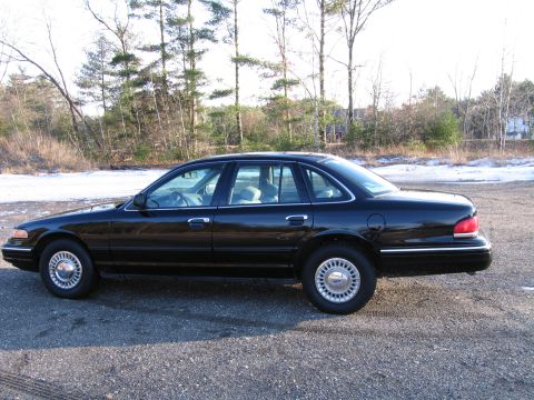 1991 Ford LTD Crown Victoria - Side profile of a black 1991 Ford Crown Victoria LTD sedan parked on a gravel lot.