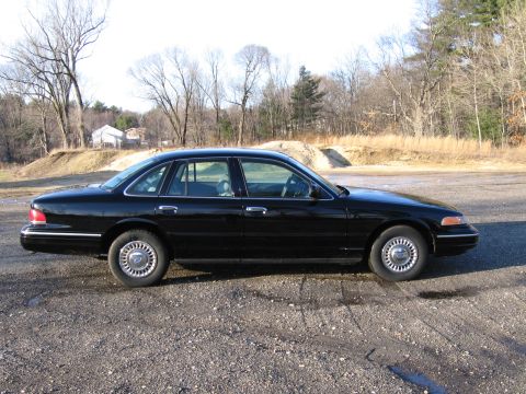 1991 Ford LTD Crown Victoria - Side profile of a black 1991 Ford Crown Victoria LTD sedan parked on a gravel lot.