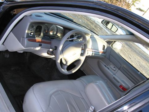 1991 Ford LTD Crown Victoria - The interior of a car features a light gray dashboard and seats, with a wood-grain trim accent on the dash.
