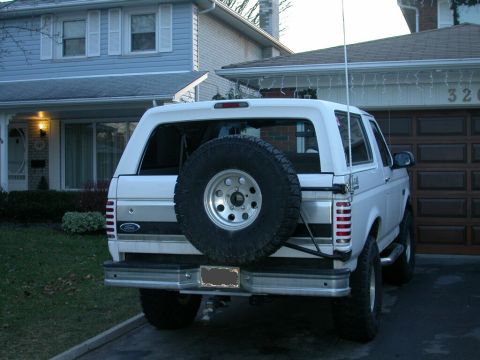 1996 Ford Bronco - Rear view of a white Ford Bronco SUV parked in front of a suburban house and garage.