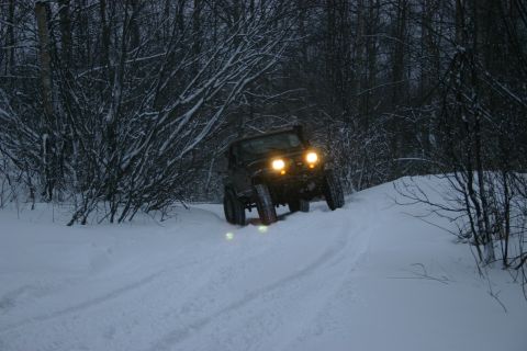 2003 Jeep TJ - 2003 Jeep TJ navigates a snowy path through a forest during winter.