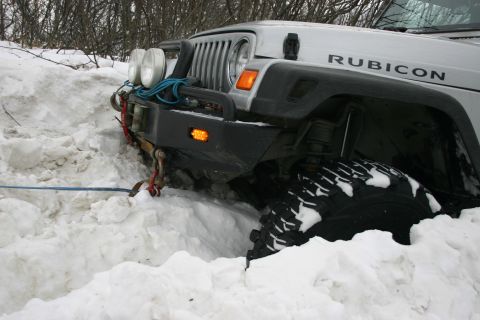 2003 Jeep TJ - A silver Jeep Wrangler Rubicon is partially buried in snow, with a winch line attached to its front bumper.