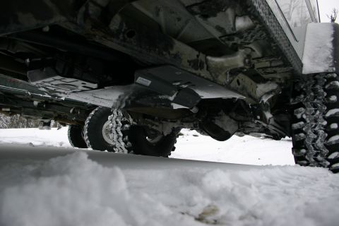2003 Jeep TJ - The undercarriage of a four-wheel-drive vehicle is visible, covered in snow, with its tires and suspension components prominent.