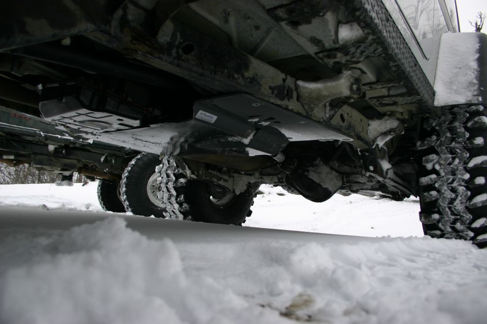 Underside of a 4x4 vehicle in snow, showing suspension and skid plates