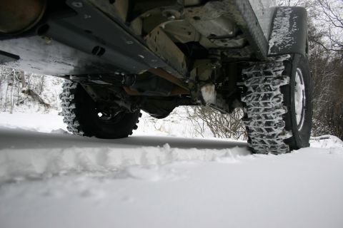 2003 Jeep TJ - The underside of a vehicle, including its suspension and tires, is visible as it sits in a snowy environment.