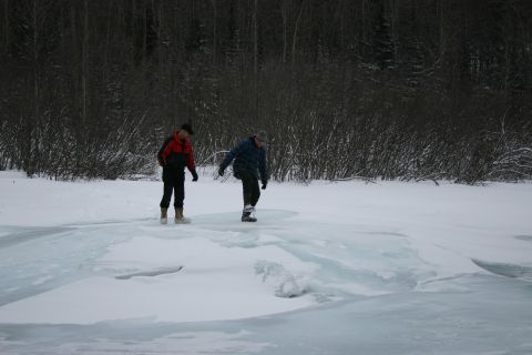 2003 Jeep TJ - Two individuals traverse a frozen landscape with dense trees in the background.