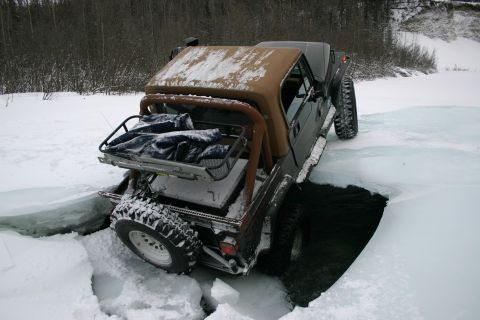 2003 Jeep TJ - Jeep TJ is partially submerged in a hole in the ice during winter.