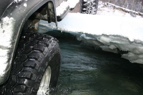 2003 Jeep TJ - A 2003 Jeep TJ navigates through a partially frozen body of water, with snow and ice lining the banks.
