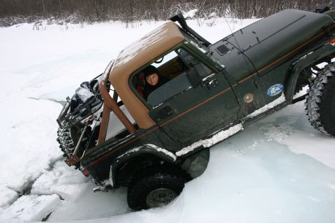2003 Jeep TJ - A green 2003 Jeep Wrangler TJ is stuck in ice, with its driver looking out from the cabin.