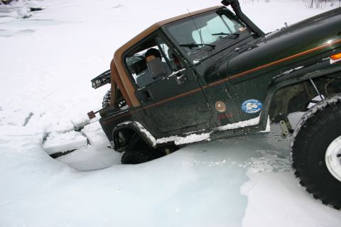 2003 Jeep TJ - Jeep TJ partially submerged in icy water, with its front wheel deep in the frozen surface.