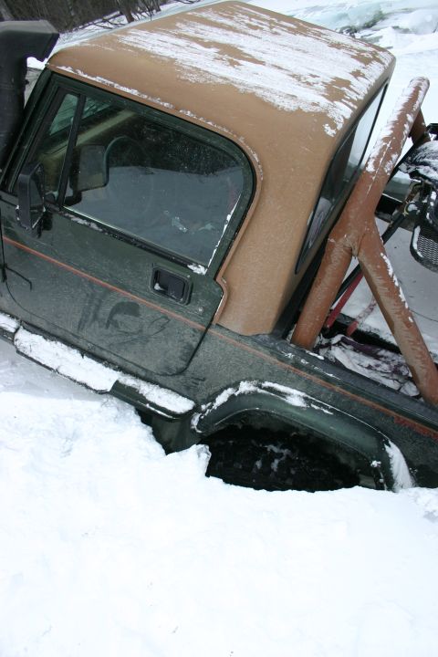 2003 Jeep TJ - A green Jeep Wrangler with a tan soft top is stuck in deep snow.