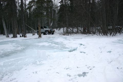 2003 Jeep TJ - A silver Jeep Wrangler is parked in a snowy forest next to a partially frozen lake.