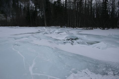 2003 Jeep TJ - A winter scene depicts ice patterns on a frozen lake or river, with a treeline visible in the distance.