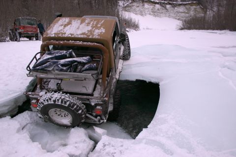 2003 Jeep TJ - A brown Jeep CJ-7 equipped with a plow is seen in a snowy landscape.