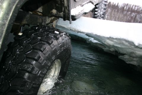 2003 Jeep TJ - An off-road vehicle navigates through a narrow channel of icy water, with another vehicle partially visible in the background.