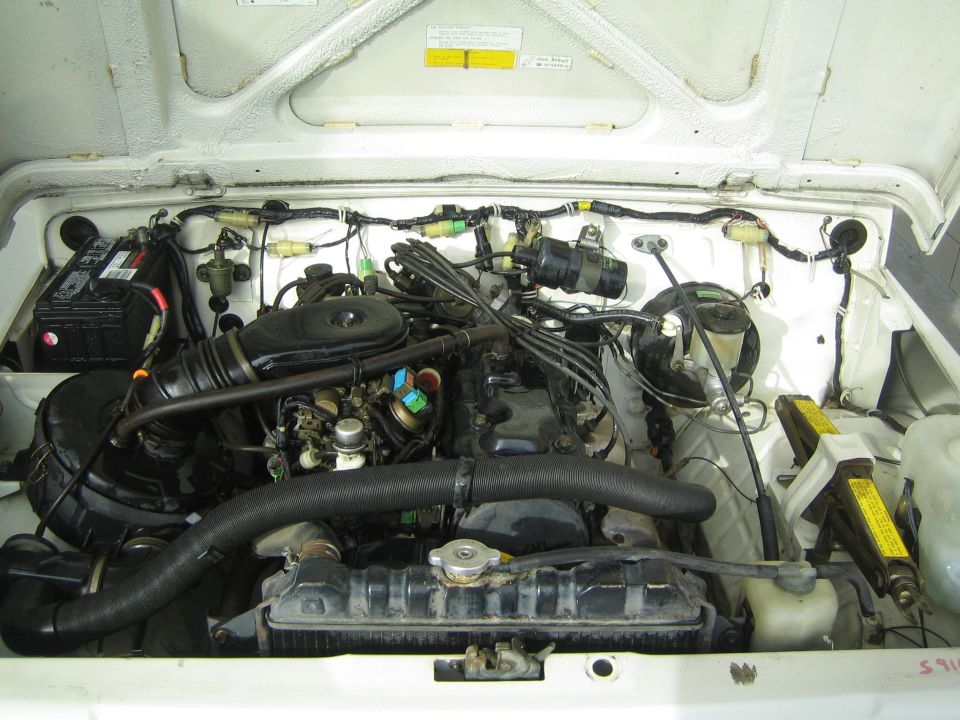 engine bay with battery, radiator, and engine components visible