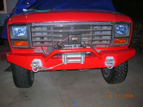 1985 Ford Bronco - Front view of a red Ford Bronco with an aftermarket bumper and winch installed.
