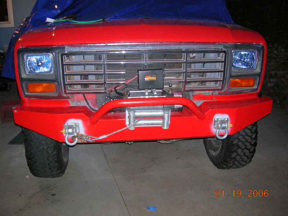 Red Ford Bronco front with tubular bumper, winch, and off-road tires
