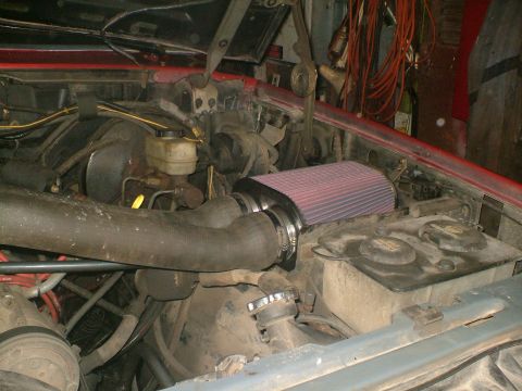 1989 Ford Bronco - The engine bay shows an aftermarket air filter and various hoses, with the brake fluid reservoir in view.