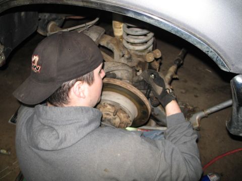 1995 Ford Bronco - A person works on the wheel bearing and brake assembly of a vehicle.