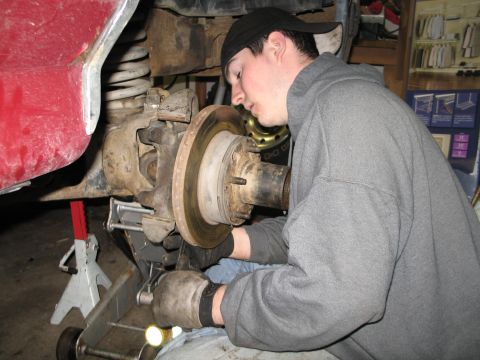 1995 Ford Bronco - Mechanic performs maintenance on a vehicle's wheel hub and brake rotor assembly.