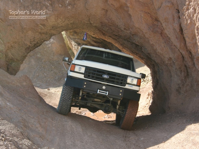 White 1988 Ford Bronco navigating a narrow rock tunnel