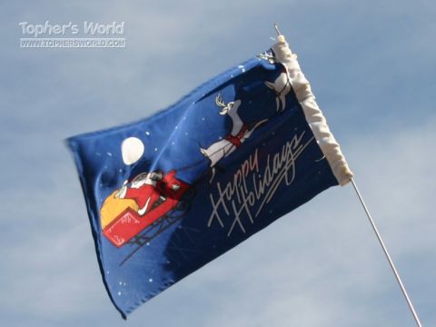 1988 Ford Bronco - Blue holiday flag with Santa, reindeer, and 'Happy Holidays' text against a blue sky.