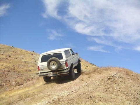1988 Ford Bronco - White Ford Bronco climbing a dirt hill.