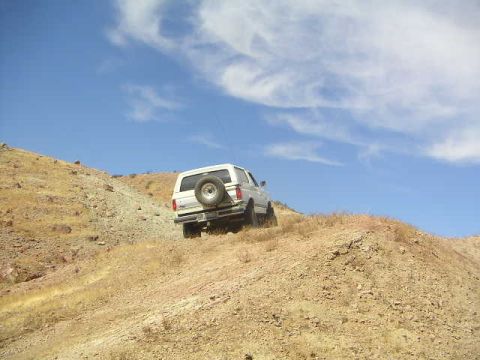 1988 Ford Bronco - A 1988 Ford Bronco navigates a steep, arid incline on a sunny day.