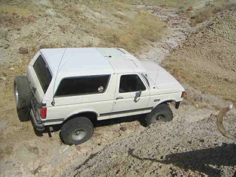 1988 Ford Bronco - This 1988 Ford Bronco, equipped with a camper shell, navigates a , off-road terrain.